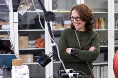 Portrait of a smiling Raffaella De Vita, in a green sweater, in her lab