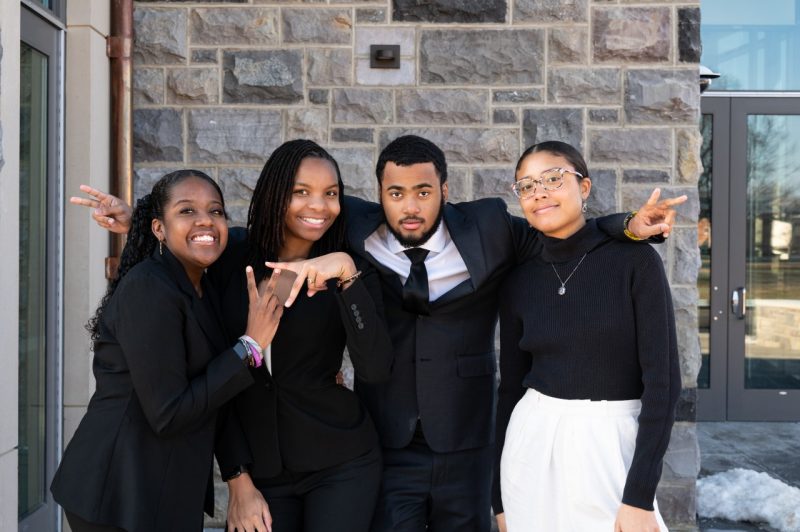 Four Virginia Tech undergraduate students who serve as interns in the Student Opportunity and Achievement Resources Program are gathered in front the Creativity and Innovation District dorm. 