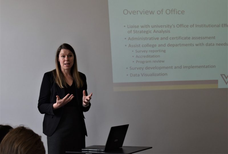 Kacy Lawrence in front of an audience with a slide noting the work of her data office