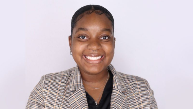 VT SOAR Student Intern Chyna Carter smiles wearing a black shirt with a patterend suit jacket that is grey with black and light brown stripes